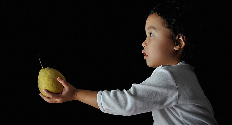 Child offering a pear.